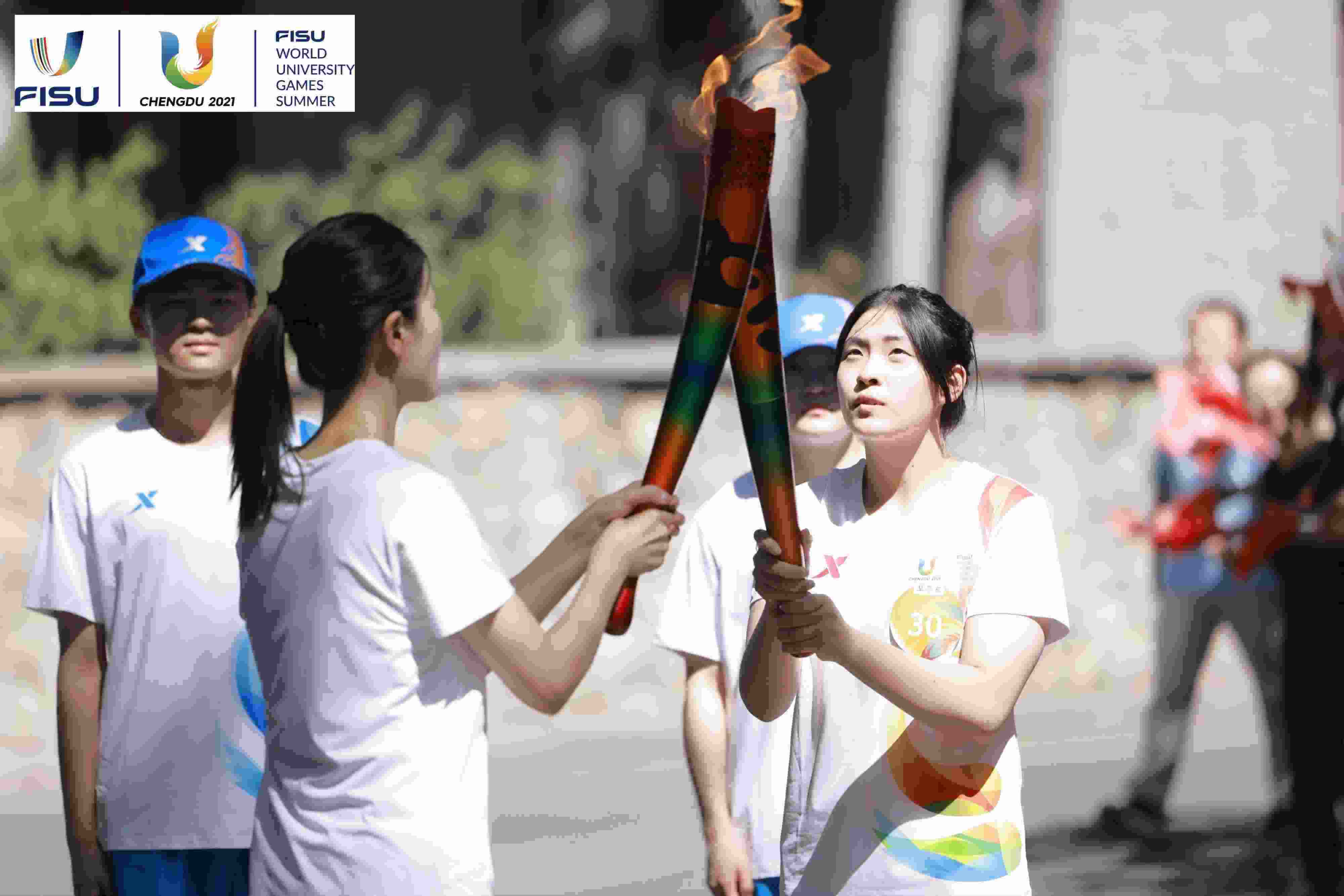 兩名大運會火炬手進行火炬?zhèn)鬟f。 圖片來源：成都大運會執(zhí)委會供圖