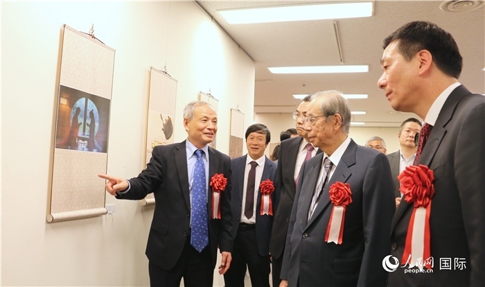 “湖州印象”攝影展主創(chuàng)、世界華人攝影協(xié)會副會長馮學敏向吳江浩大使、福田康夫前首相等嘉賓介紹展出作品。（人民網(wǎng) 許可攝）