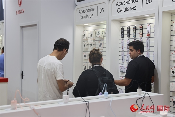 幾名參觀者在一個展臺前了解手機配件。（人民網記者 時元皓攝）