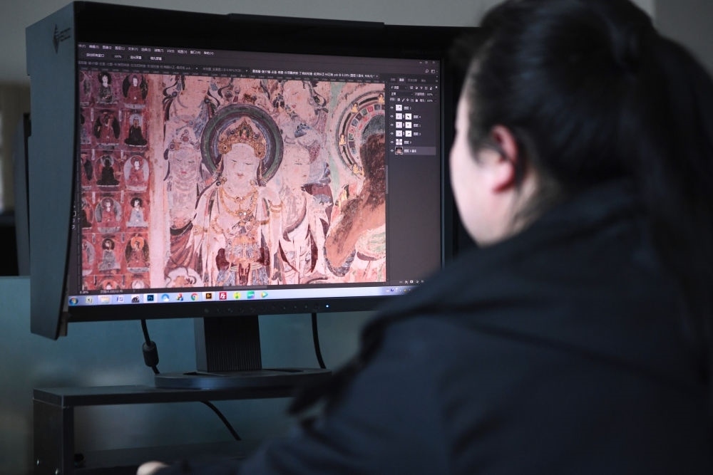 敦煌研究院文物數(shù)字化保護(hù)團(tuán)隊(duì)圖像處理人員年海麗在拼接壁畫(huà)圖像（2023年4月25日攝）。數(shù)字化探索為莫高窟的保護(hù)與傳承開(kāi)辟了全新路徑，數(shù)字技術(shù)讓敦煌文物走出洞窟，跨出國(guó)門(mén)，走向“永久保存、永續(xù)利用”。新華社記者 陳斌 攝