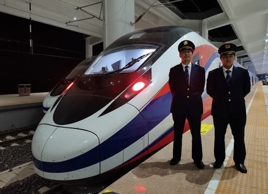 劉銀能（右一）與中國師父鄔俊鴻在動車組前合影。受訪者供圖