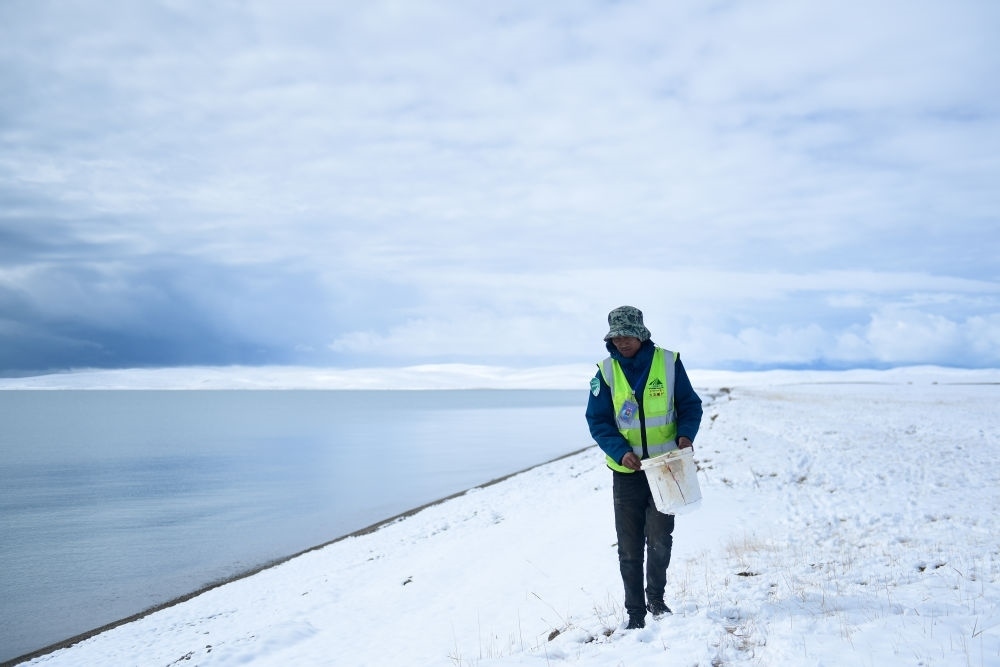 2021年10月20日，在青海省果洛藏族自治州瑪多縣扎陵湖鄉(xiāng)勒那村，三江源國(guó)家公園黃河源園區(qū)生態(tài)管護(hù)員在扎陵湖邊撿拾垃圾。新華社記者 張龍 攝