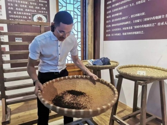 2023“一帶一路”媒體合作論壇聯(lián)合采訪團團員在非遺文化展示館體驗中藥炮制技藝。（本報記者 黃超攝）