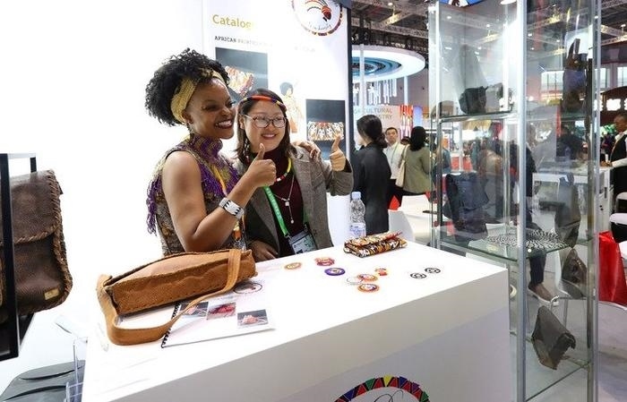 11月6日，一位參觀者（右）在第六屆進(jìn)博會國家展南非展臺試戴傳統(tǒng)首飾。