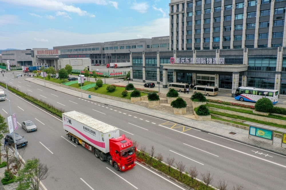 2023年10月11日，滿載筆記本電腦配件、發(fā)電機(jī)組件等產(chǎn)品的西部陸海新通道跨境公路班車從重慶南彭公路保稅物流中心駛出，將途經(jīng)廣西憑祥，直達(dá)越南（無人機(jī)照片）。新華社記者 黃偉 攝