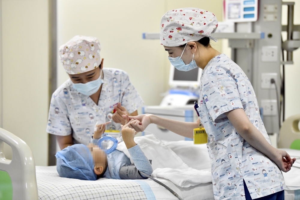 在山東省棗莊市婦幼保健院兒童ICU病房，醫(yī)護人員為完成靶向治療藥物諾西那生鈉的4歲脊髓性肌萎縮癥患兒加油鼓勁（2022年1月1日攝）。諾西那生鈉注射液是我國首個獲批治療脊髓性肌萎縮癥的進口藥物，2019年進入中國市場時，每針價格近70萬元。在2021年國家醫(yī)保目錄藥品談判中，以3.3萬元每針的價格進入新版醫(yī)保藥品目錄。新華社記者 郭緒雷 攝