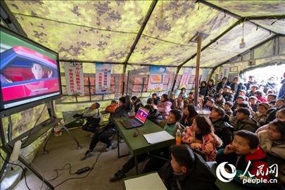 12月22日，在積石山縣大河家鎮(zhèn)大河村安置點，陸軍76集團軍某旅搭建的“臨時學(xué)?！眱?nèi)，小朋友正在看動畫片。人民網(wǎng)記者 翁奇羽攝