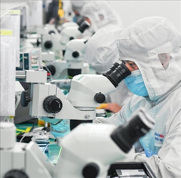 在位于武漢中國(guó)光谷的光電器件研發(fā)制造商——武漢光迅科技股份有限公司生產(chǎn)車間內(nèi)，技術(shù)人員在光模塊生產(chǎn)線作業(yè)（2023年4月11日攝）。程敏攝/本刊