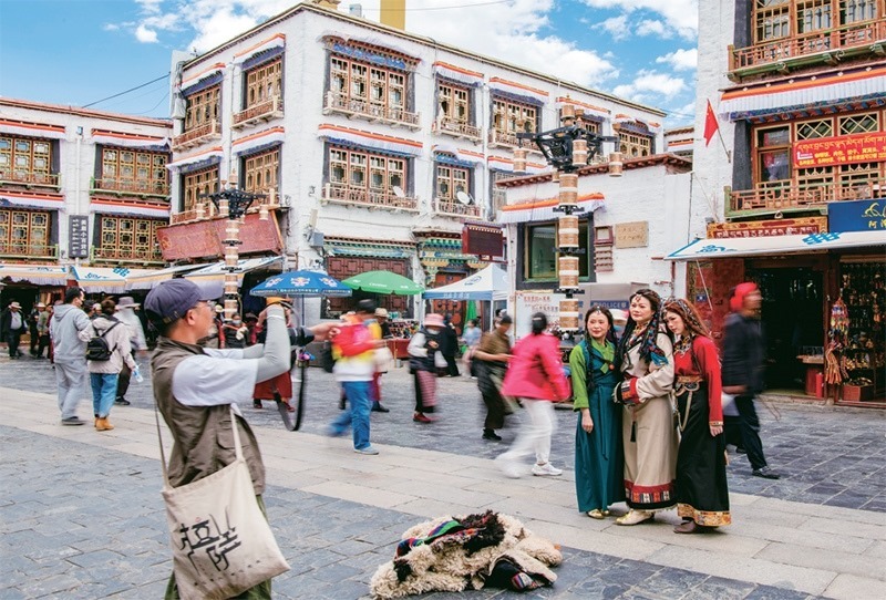 千年八廓街，見證民族團結(jié)。2021年7月，習近平總書記來到位于西藏拉薩老城區(qū)的八廓街，感慨地說：“千年八廓街，是我們各民族建起來的八廓街。各民族文化在這里交流交往交融，我們中華民族的大家庭在這里其樂融融?！眻D為2023年6月13日，游客身著藏裝在八廓街拍照留念。 新華社記者 姜帆/攝