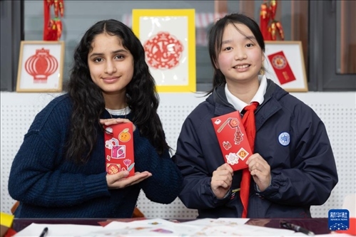 1月28日，美國(guó)馬斯卡廷中學(xué)學(xué)生（左）和復(fù)旦大學(xué)第二附屬學(xué)校學(xué)生展示互相送出的寫(xiě)有寄語(yǔ)祝福的紅包。 新華社記者 王翔 攝