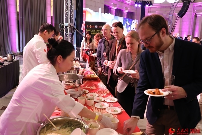 當(dāng)?shù)貢r(shí)間3月7日晚，華盛頓聯(lián)合車站廣場(chǎng)舉行駐美使團(tuán)“使館主廚挑戰(zhàn)賽”。圖為當(dāng)?shù)孛癖娫谥袊古_(tái)前體驗(yàn)中國美食。人民網(wǎng)記者 李志偉攝