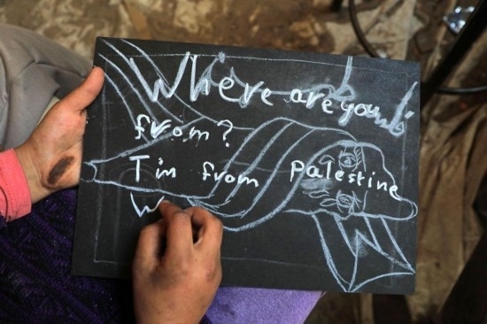 2023年12月28日，一名學(xué)生在加沙地帶南部城市拉法一所學(xué)校的臨時(shí)教室中寫(xiě)下“我來(lái)自巴勒斯坦”的字樣。新華社發(fā)（里澤克·阿卜杜勒賈瓦德攝）