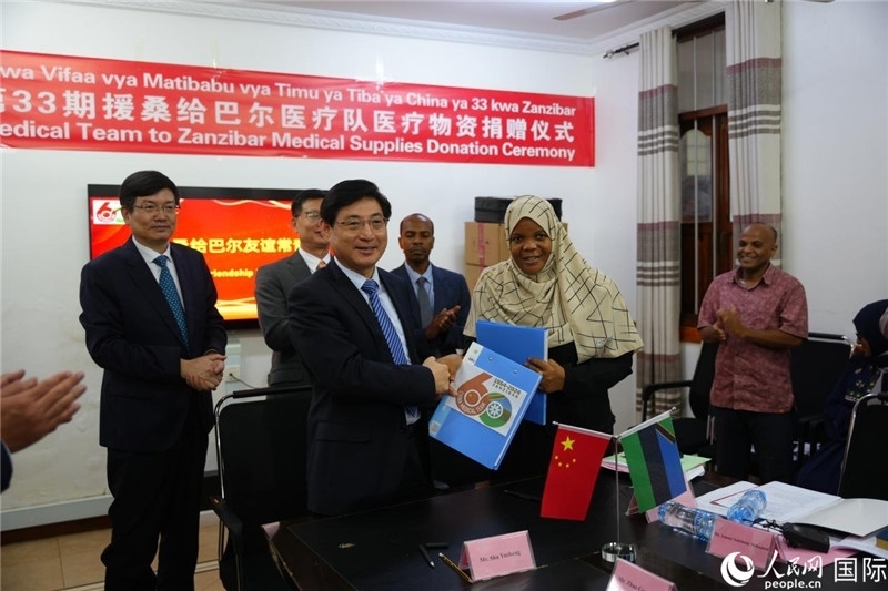 江蘇省蘇北人民醫(yī)院黨委書記束余聲與桑衛(wèi)生部首席秘書哈比巴交換捐贈(zèng)書。中國(guó)援桑醫(yī)療隊(duì)供圖