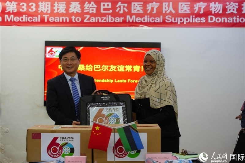 江蘇省蘇北人民醫(yī)院黨委書記束余聲捐贈(zèng)物資與桑衛(wèi)生部首席秘書哈比巴。中國(guó)援桑醫(yī)療隊(duì)供圖