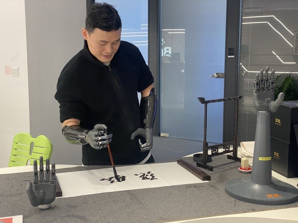 2024年3月29日，在浙江強腦科技有限公司展廳內(nèi)，失去雙手的產(chǎn)品體驗官倪敏成依靠智能仿生手寫毛筆字。新華社記者 魏一駿 攝