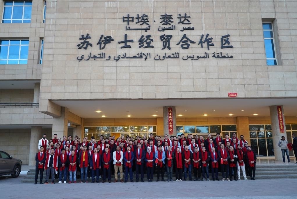 2024年2月11日，在位于埃及蘇伊士省的中?！ぬ┻_(dá)蘇伊士經(jīng)貿(mào)合作區(qū)，中埃員工在合作區(qū)辦公大樓前合影拜年。新華社發(fā)（泰達(dá)合作區(qū)供圖）