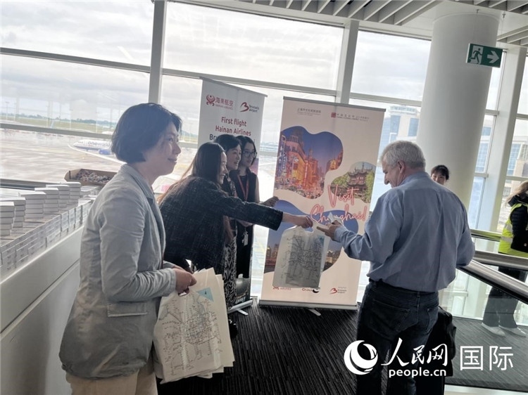 圖為工作人員向乘客發(fā)放復(fù)航首班禮物。 牛瑞飛攝