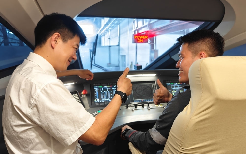 2023年8月25日，在印度尼西亞萬隆的雅萬高鐵德卡魯爾動車所內(nèi)，中國師傅穆振（左）向印尼火車司機塞蒂亞萬講解動車組出庫前的上電作業(yè)。新華社記者 徐欽 攝