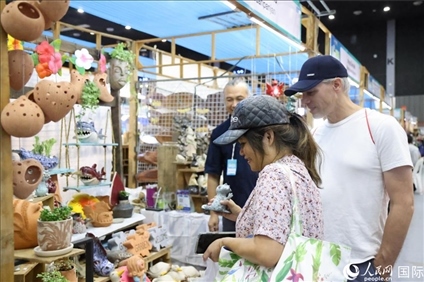游客在蘭納博覽會特色展位上選購工藝品。人民網(wǎng)記者楊一攝
