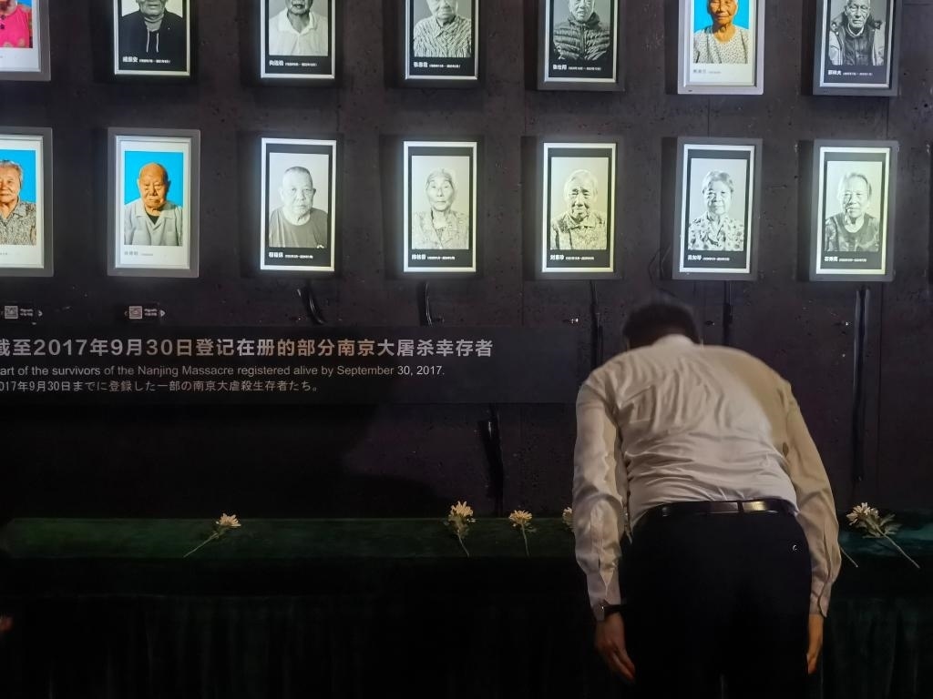 7月18日，人們向離世的南京大屠殺幸存者獻(xiàn)花、鞠躬。新華社記者邱冰清 攝