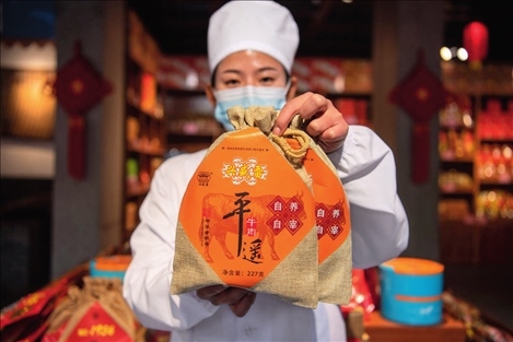 在位于山西省晉中市平遙縣的平遙古城南大街的一家平遙牛肉店內(nèi)，工作人員展示一款牛肉產(chǎn)品（資料照片）楊晨光攝 / 本刊