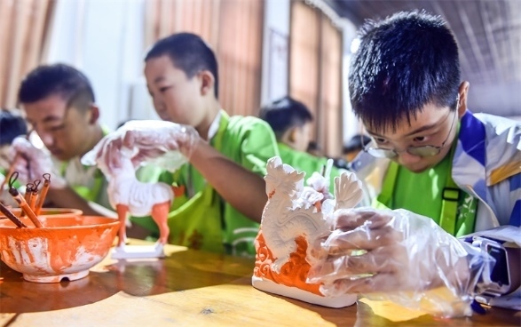 小朋友們在洛陽市孟津區(qū)朝陽鎮(zhèn)南石山村體驗唐三彩素胎施釉技藝。圖片來源：視覺中國