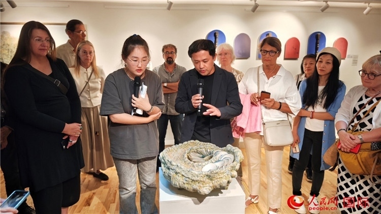 參展人、景德鎮(zhèn)陶瓷大學(xué)設(shè)計(jì)藝術(shù)學(xué)院副院長(zhǎng)余劍峰（中）向來賓介紹參展作品。人民網(wǎng)記者 殷淼攝