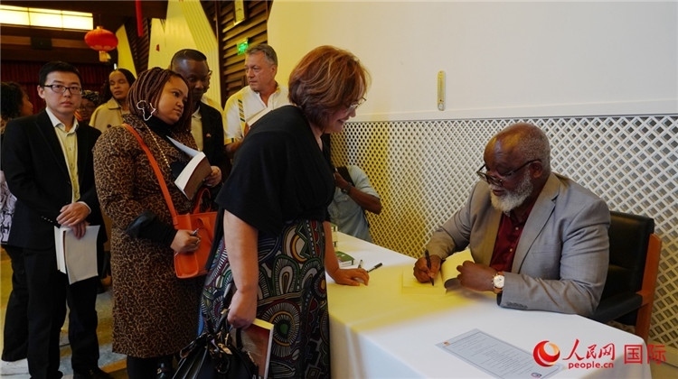 譚哲理在活動(dòng)現(xiàn)場(chǎng)簽名贈(zèng)書。人民網(wǎng) 劉暢攝