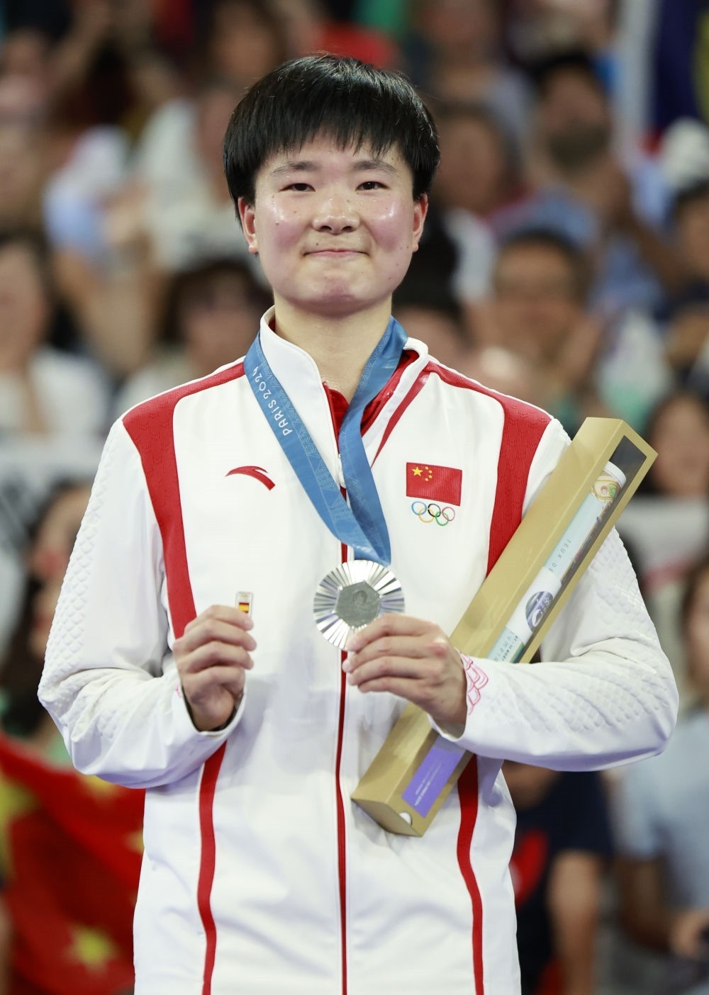 巴黎奧運(yùn)會羽毛球女子單打亞軍、中國選手何冰嬌在頒獎儀式上一手握著銀牌，一手握著西班牙奧委會徽章（2024年8月5日攝）。新華社記者 任正來 攝