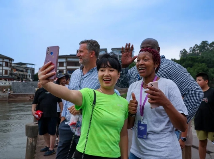 2024“一帶一路”媒體合作論壇聯(lián)合采訪調(diào)研行成員在樂山蘇稽古鎮(zhèn)與游客合影留念。本報記者 伊霄攝