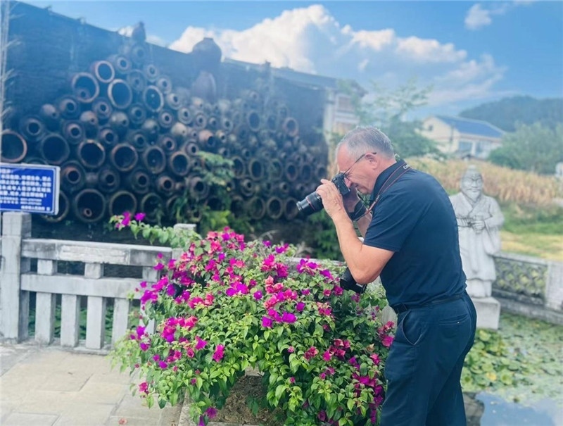 遠(yuǎn)處黔北民居錯落有致，近處一只黑色的蝴蝶穿梭于粉紫色三角梅花叢間隙，與俄羅斯“大歐亞”總編輯弗拉基米爾·別列日內(nèi)赫的鏡頭玩起了捉迷藏，“你追我逃，不亦樂乎”。（張亞欣攝）