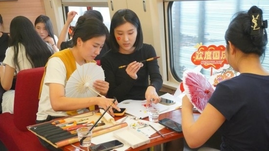 10月1日，旅客們在G1634次列車上給油紙傘作畫。新華社記者周義 攝