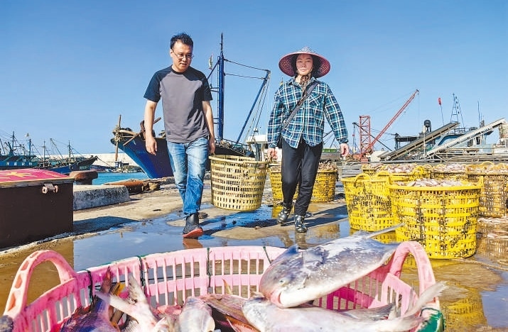 許小斌（左）和漁民一起搬運(yùn)海鮮。本報(bào)記者 付 文攝