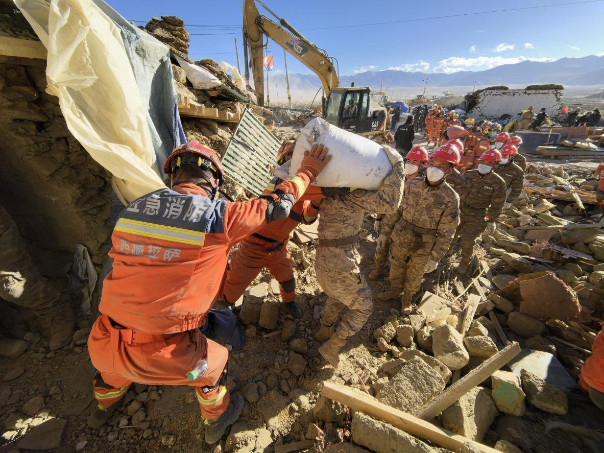 1月11日，定日縣長(zhǎng)所鄉(xiāng)古榮村，應(yīng)急消防等救援人員排隊(duì)接力搶運(yùn)掩埋在倒塌房屋下的群眾財(cái)物。人民日?qǐng)?bào)記者楊翹楚攝