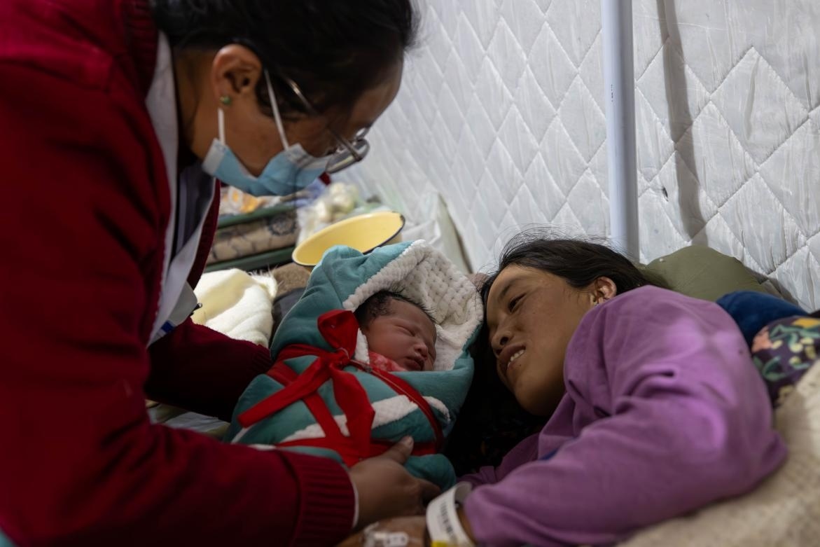 1月10日，定日縣中心醫(yī)院的婦產(chǎn)科醫(yī)生悉心照看一位母親和她懷里的新生兒。人民日?qǐng)?bào)記者張武軍攝