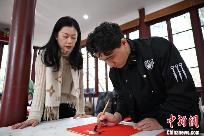 1月20日，外籍留學(xué)生在西泠印社社員李硯指導(dǎo)下寫福。當(dāng)日，來(lái)自巴西、馬來(lái)西亞、加納、哈薩克斯坦的外籍留學(xué)生在浙江杭州西泠印社體驗(yàn)福貼、春聯(lián)和篆刻，感受古老的中國(guó)傳統(tǒng)文化。中新社記者 王剛 攝