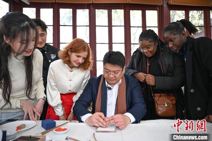 1月20日，篆刻家王臻向外籍留學(xué)生展示篆刻印章。當(dāng)日，來(lái)自巴西、馬來(lái)西亞、加納、哈薩克斯坦的外籍留學(xué)生在浙江杭州西泠印社體驗(yàn)福貼、春聯(lián)和篆刻，感受古老的中國(guó)傳統(tǒng)文化。中新社記者 王剛 攝