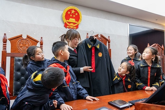 圖②：干警向同學(xué)們介紹法袍。