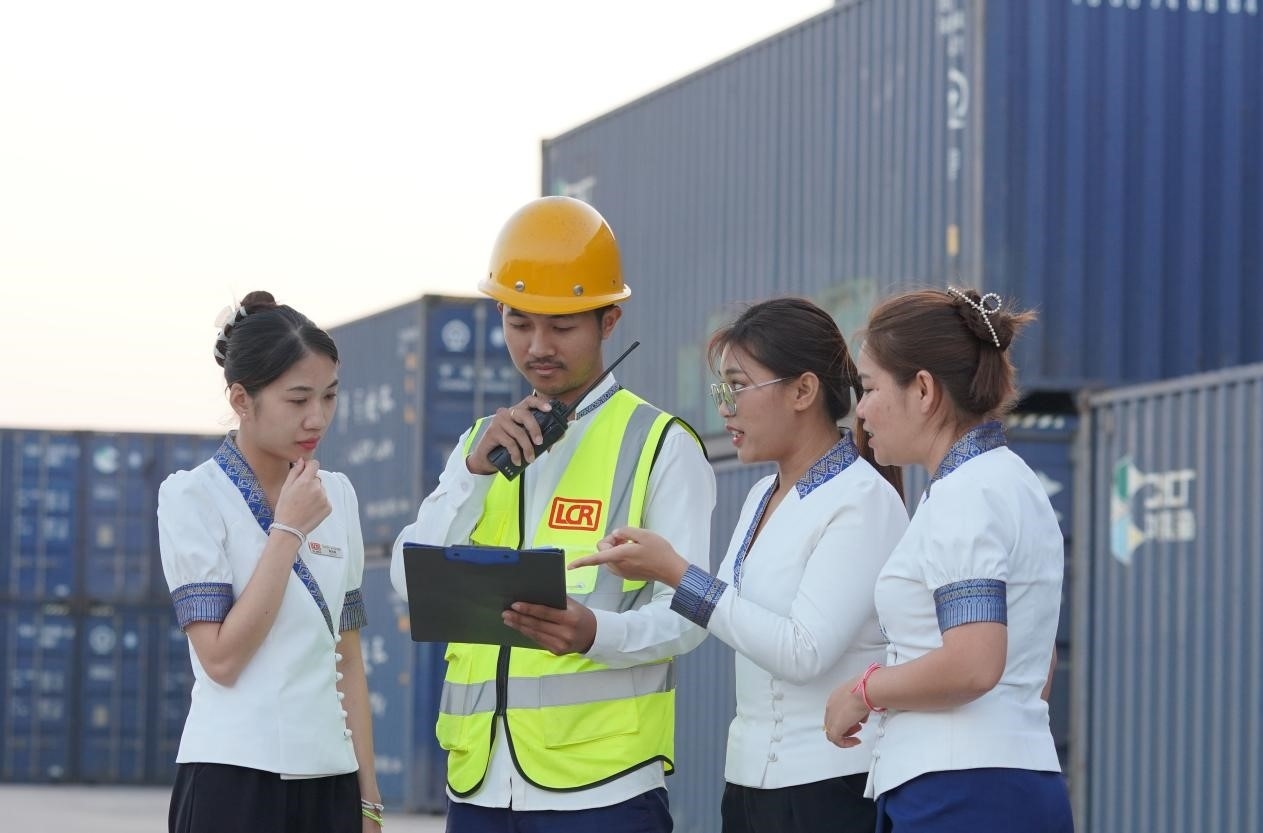 萬象南站貨運(yùn)值班員陳尼啦（左一）與同事在一起討論工作。老中鐵路有限公司供圖