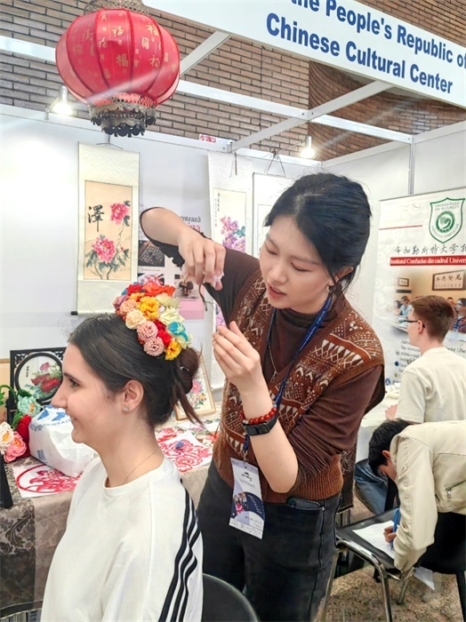 展覽正值羅馬尼亞迎春花節(jié)，國(guó)際中文教師志愿者潘婧穎向游客們介紹了國(guó)家非物質(zhì)文化遺產(chǎn)——福建泉州的簪花文化。布加勒斯特大學(xué)孔子學(xué)院供圖。